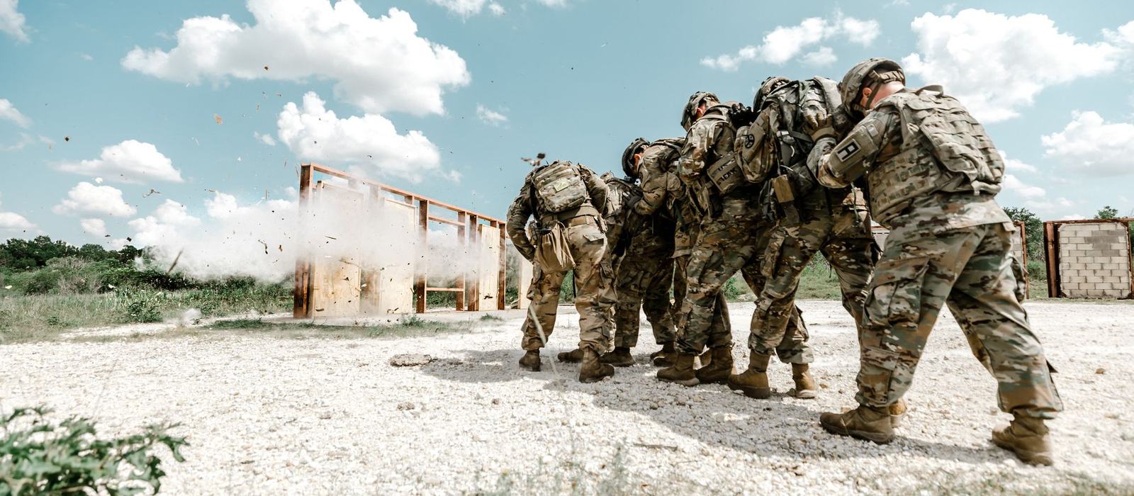 Soldiers moving together through a breach during a field exercise